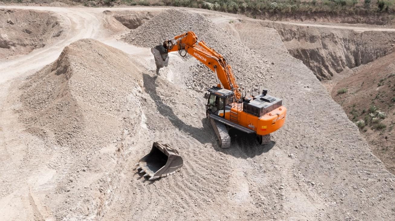 An advanced autonomous excavator operating on a construction site with digital monitoring screens in the background