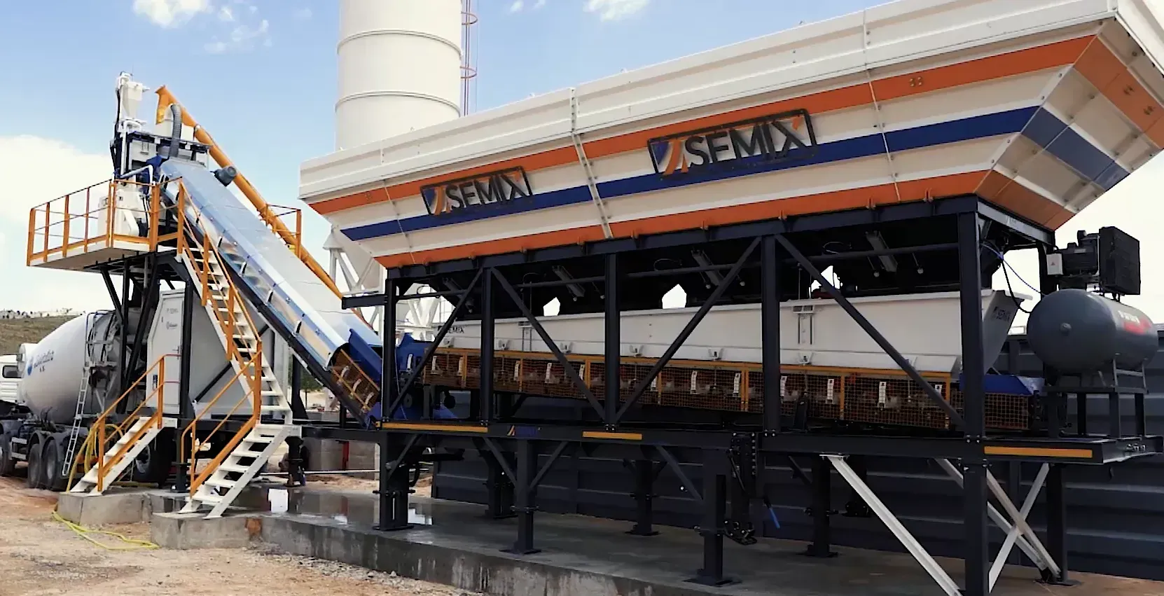 Mobile 60 S4 Concrete Batching Plant — The SEMIX Mobile 60 S4 Concrete Batching Plant is a high-efficiency, mobile batching solution designed for construction professionals requiring rapid relocation, fast assembly, and consistent, high-volume concrete production. With an output capacity of 60 m³/h, the Mobile 60 S4 stands out for its patented inline aggregate bin design, which allows for aggregate feeding with only one ramp and eliminates the need for a pre-feeding conveyor. This unique feature streamlines setup and operational logistics, making it both cost-effective and space-efficient. The entire plant can be assembled in just two days, with a compact and transportable structure engineered for effortless movement between job sites. SEMIX’s engineering expertise allows for bespoke adaptations, permitting the Mobile 60 S4 to be tailored according to specific project requirements, from mixer types to bin modifications.
  
  At the plant’s heart, 1 m³ compacted concrete output mixers are standard, with options to integrate single shaft, twin shaft, or planetary mixers based on the application. All mixing operations are governed by a robust mixer-control software, supporting full automation for error-free, high-speed batching cycles. The use of advanced alloys in mixer blades (Ni-Hard 4 chrome-nickel cast iron) and HARDOX 450 in internal wear plates ensures exceptional resistance to abrasion and deformation—a necessity for continuous high-volume concrete mixing. The mixers benefit from an automatic SKF-Lincoln lubrication system, integrated with the PLC and SCADA systems, guaranteeing long-term durability and minimal manual maintenance.
  
  The plant incorporates high-quality, internationally sourced components: cement and water weighing systems with WAM (Italy) valves and OLI (Italy) vibrators; aggregate bins with reinforced trapezoidal construction for longevity; FESTO (Germany) pneumatic control for precision gate operation; and conveyor systems with EP 125/4 belting, SNH-series greased bearings, and integrated safety features such as emergency stops and pull-rope switches. A galvanized, quick-clean concrete discharge funnel, robust walkways, handrails, and maintenance safety switches ensure user safety and efficient workflows.
  
  SEMIX’s brand identity centers on innovation, reliability, customization, and global reach. The company's engineering-driven approach, highlighted by patented structural features and modular options, positions it as a forward-looking, customer-focused manufacturer, ready to deliver tailored batching plant solutions anywhere in the world via a network of exclusive distributors.
  
  The primary target audience for the Mobile 60 S4 includes construction contractors, concrete suppliers, and infrastructure developers who demand high throughput, operational flexibility, low maintenance, and equipment durability. Pain points addressed include minimizing setup time, reducing transport and logistics costs, and ensuring consistent production quality under challenging and high-demand conditions.
  
  Marketing angles emphasize the plant's rapid assembly, unique patented bin technology, advanced automation, heavy-duty build quality, premium European components, and SEMIX’s readiness to customize per project specifications. Emotional triggers can be found in the assurance of uninterrupted, professional production, the safety and peace of mind brought by robust engineering, and the confidence in SEMIX’s international support network capable of providing bespoke solutions worldwide.